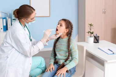 Doktor klinikte boğazı ağrıyan küçük bir kızı muayene ediyor.