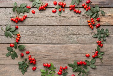 Ahşap zemin üzerinde taze gül kalçası çileklerinden yapılmış çerçeve