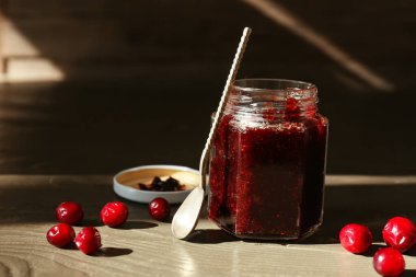 Ahşap arka planda bir kavanoz lezzetli yaban mersini reçeli.