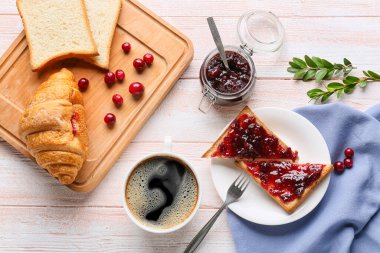 Lezzetli yaban mersini reçelli tostlar, bir fincan kahve ve hafif ahşap arka planda kruvasan.