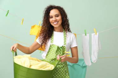 Çamaşır sepeti ve renkli mandallı genç Afro-Amerikalı kadın.