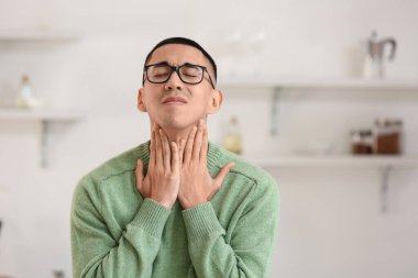 Evde boğazı ağrıyan Asyalı bir adam var.