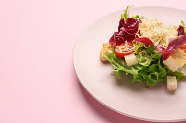 Pembe arka planda lezzetli vegan Sezar salatası, yakın plan.