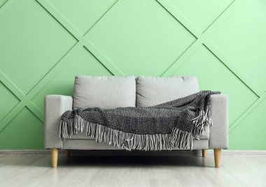 Yeşil duvarın yanında ekoseli şık kanepe