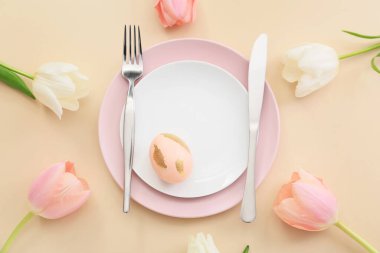 Paskalya yumurtası ve bej arka planda laleleri olan güzel bir masa.