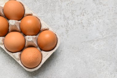 Gri arka planda taze tavuk yumurtası olan Holder, yakın plan.