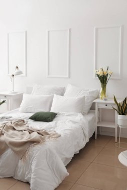 Işıklı yatak odasının içinde vazolar ve masalar var.