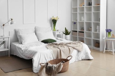 Vazolarda çiçekler olan modern yatak odasının içi.