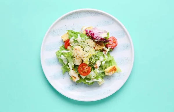 Plate with tasty vegan Caesar salad on turquoise background