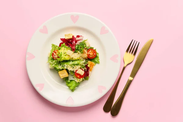 Plate with tasty vegan Caesar salad on pink background