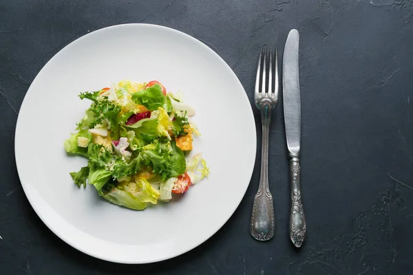 Plate with tasty vegan Caesar salad on dark background