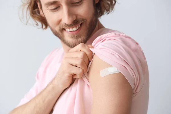 Young man with applied medical patch on grey background