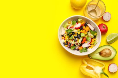 Bir kase Meksika sebze salatası, siyah fasulye, turp ve sarı arka planda malzemeler.