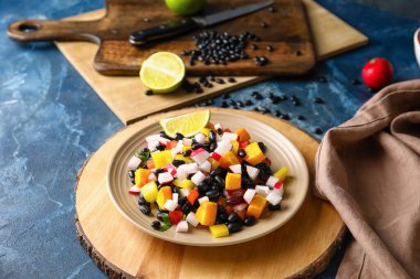 Bir tabak lezzetli Meksika salatası, siyah fasulye ve mavi arka planda turp.