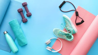 Renkli arka planda farklı spor aletleri, ayakkabılar ve kulaklık