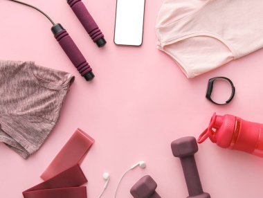 Spor malzemelerinden yapılmış çerçeve, pembe arka planda giysiler ve aletler