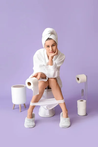 Junge Frau Bademantel Sitzt Auf Toilettenschüssel Vor Farbigem Hintergrund — Stockfoto