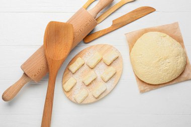 Hafif ahşap arka planda çiğ hamur, hamur ve çatal bıçaklar.