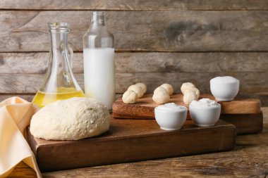 Hamurlu tahtalar, çiğ tembel hamur tatlısı ve ahşap arka plandaki malzemeler.