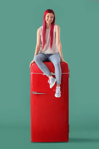 Vacker Ung Kvinna Sitter Röd Kylskåp Mot Grön Bakgrund — Stockfoto