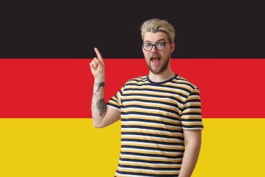 Genç adam Almanya bayrağına karşı bir şey gösteriyor.