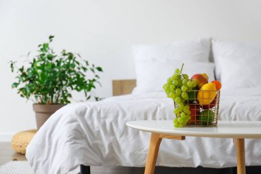 Hafif yatak odasında meyve sepetli bir masa.