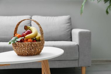 Modern oturma odasındaki masada hasır meyve sepeti.