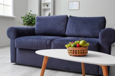 Şık oturma odasındaki masada hasır meyve sepeti.