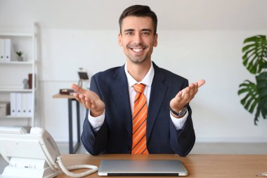 Ofisteki masada yakışıklı bir iş adamı görüntülü sohbet ediyor.