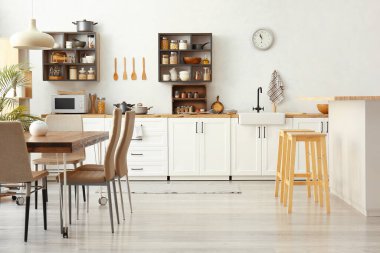Beyaz tezgahlı ve yemek masalı, aydınlık, modern mutfağın içi.