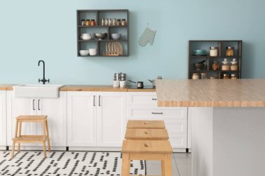 Beyaz tezgahları, rafları ve malzemeleri olan şık bir mutfak.