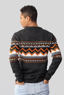 Hafif arka planda örgü süveter giyen yakışıklı Afro-Amerikalı adam.