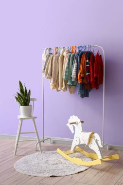 Çocuk süveterleri, sallanan atlar ve leylak duvarın yanındaki bitkilerle doldur.