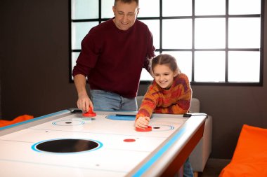 Babası ve küçük kızı içeride hokey oynuyorlar.