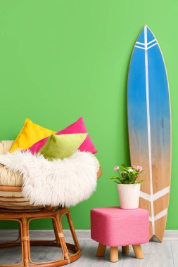 Yumuşak yastıklı rahat koltuk, oda yeşil duvarın yanında puf ve sörf tahtası