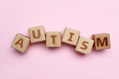 Pembe arka planda kelime AUTISM ile ahşap küpleri