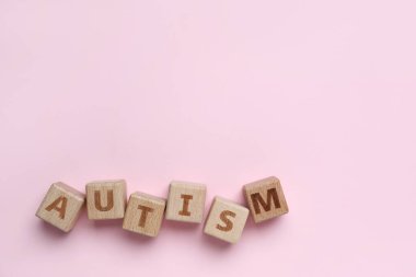Pembe arka planda kelime AUTISM ile ahşap küpleri