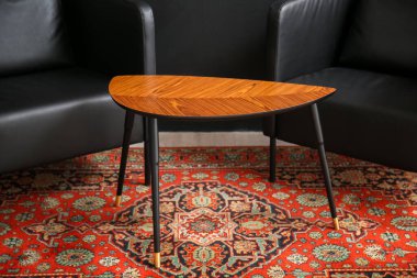 Masalı siyah koltuklar ve karanlık duvarın yanında klasik halı.