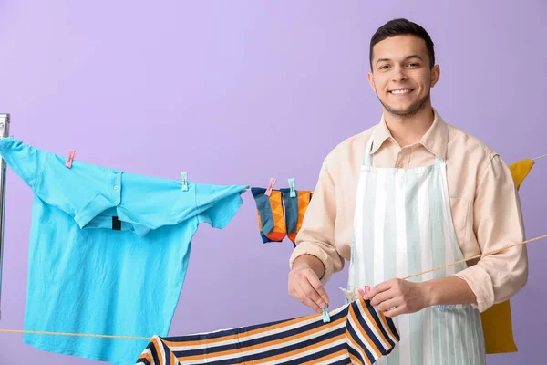 Young Man Hanging Clean Shirt Clothespin Lilac Background — Stock Photo, Image