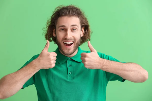 穿着T恤的英俊男子在绿色背景下竖起大拇指 — 图库照片