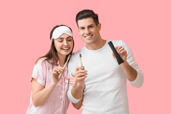 Junges Paar Mit Aktivkohle Zahnpasta Und Pinseln Auf Rosa Hintergrund — Stockfoto