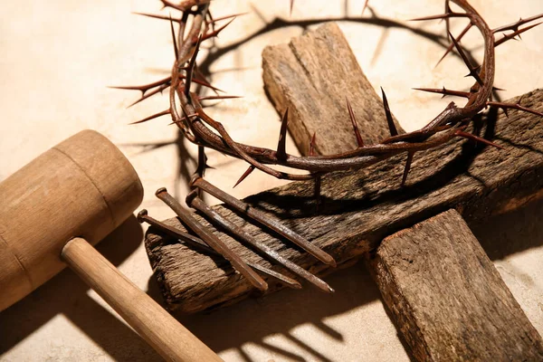 Crown of thorns with wooden cross, mallet and nails on grey background