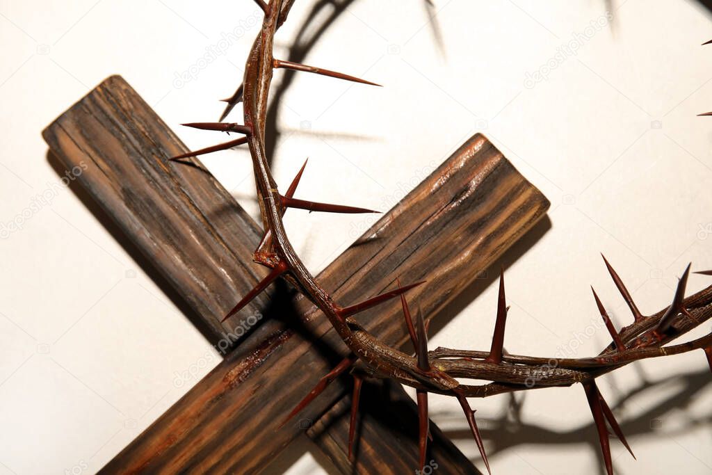 Crown of thorns with wooden cross on light background