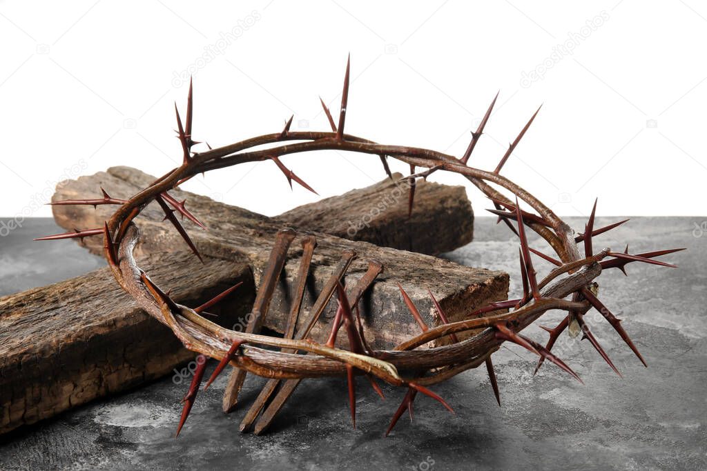 Crown of thorns with wooden cross and nails on table against white background