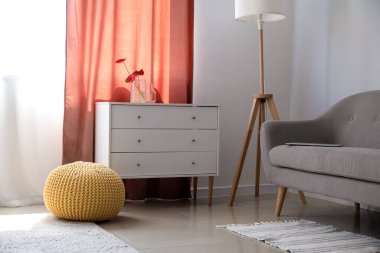 Rahat bir kanepe, çekmeceler, lamba ve puf.