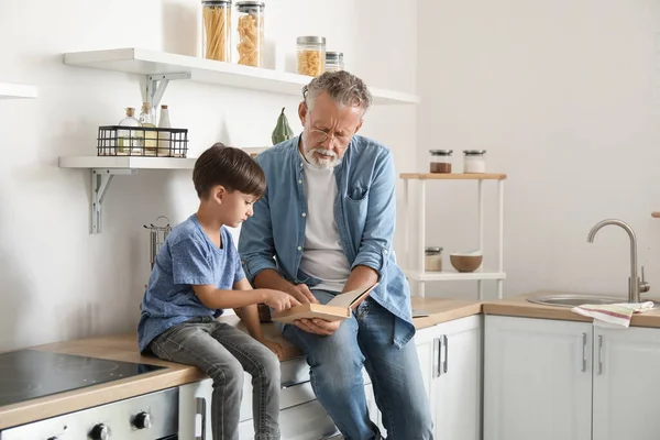 Senior Man Reading Book His Little Grandson Kitchen — Stock Photo, Image