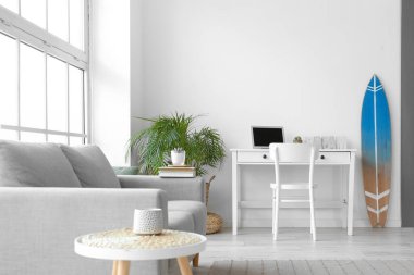 Rahat bir kanepe, iş yeri ve iç aydınlık odada sörf tahtası.