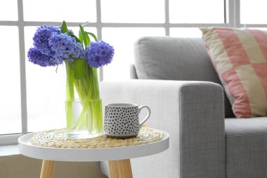 Vazo ve sümbül çiçekleri pencerenin yanındaki masada.