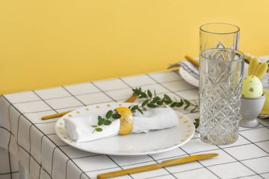Paskalya kutlaması için sarı duvarın yanında okaliptüs dallı güzel bir masa.