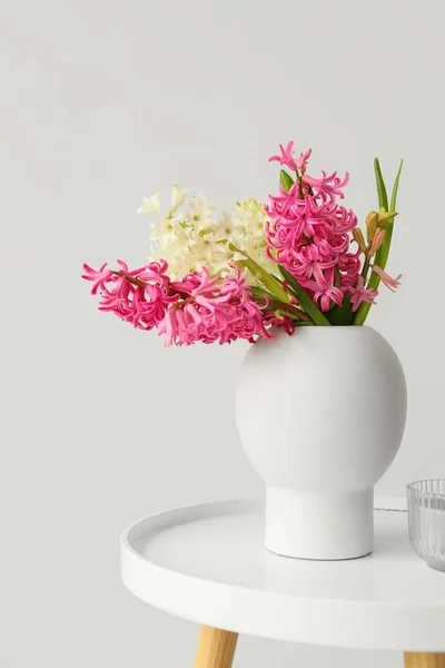 白い壁の近くのテーブルの上にヒヤシンスの花やキャンドルの花瓶 — ストック写真